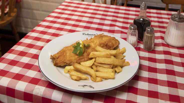 A plate of fish and chips on a checkered table cloth