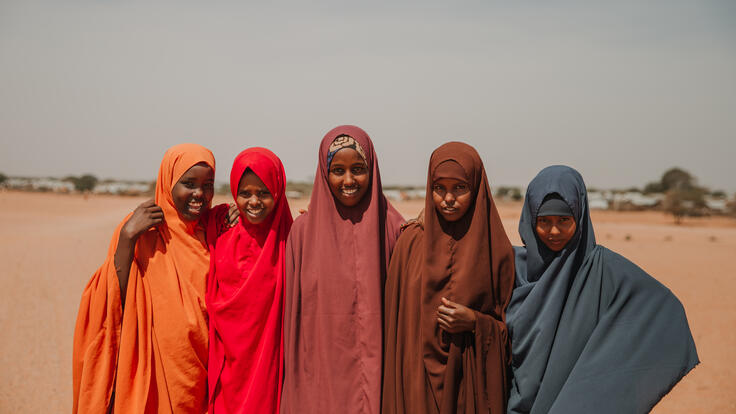 Five girls dressed in bright colours smile at the camera.