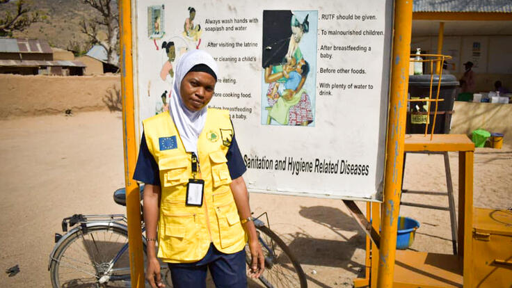 Aishatu standing by an information board