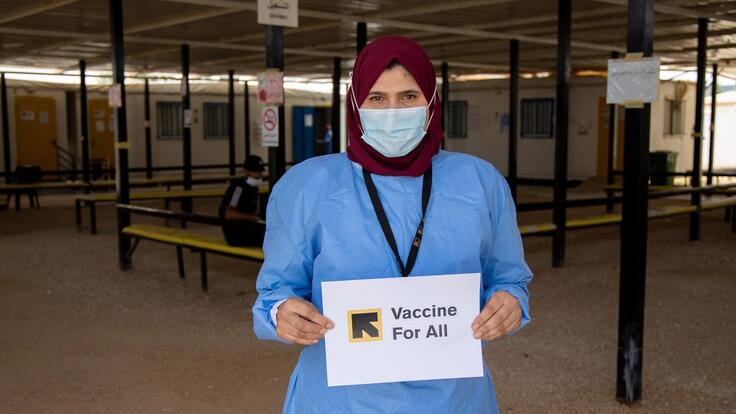 IRC senior health officer holding a sign saying "Vaccines for All"