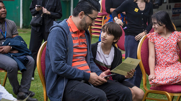 Khalil shows his son Ahmad his RISE graduation certificate.