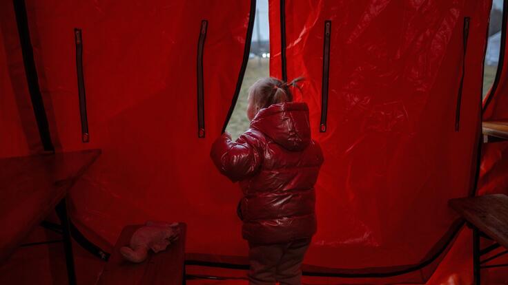 Iryna firstborn looking out of a tent in Poland 