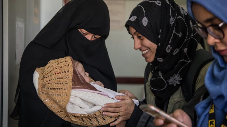 New mother Mona Mohammed shows her baby to IRC health workers at a clinic in Sana'a