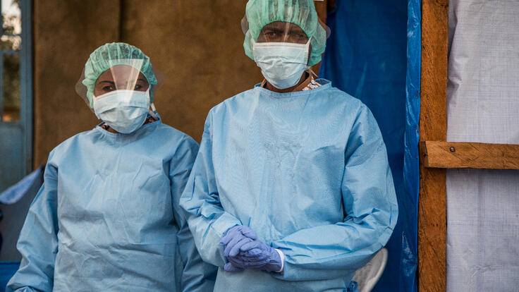 Two IRC staff members, a woman and a man, wear full personal protective equipment (PPE) during an outbreak of Ebola in the Democratic Republic of Congo.