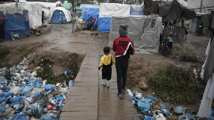 A child and a toddler walk across a bridge in Moria refugee camp