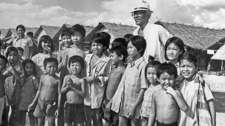 Bayard Rustin stands with a group of refugee children in Southeast Asia for a photo
