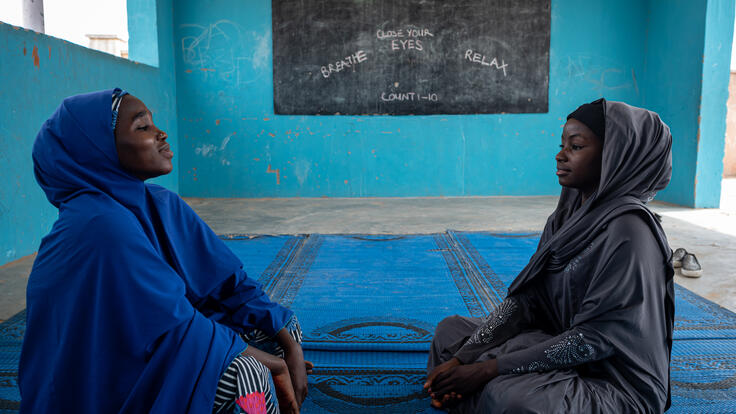 Teacher Falmata and her student, a 17-year-old girl named Hauwa, sit on a mat doing deep breathing exercises for mindfulness