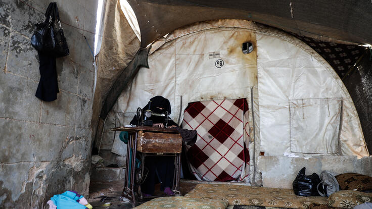 Wa'ad sews face masks at her sewing machine in her makeshift shelter in northwestern Syria.