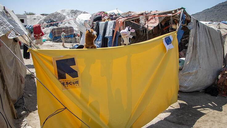 Outside in Al-Manshar camp in Yemen, a yellow tarp is set up between tents. Just above the tarp are a fox and cow puppet, part of the show to teach children about COVID-19. 