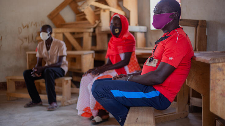 Komonda, 41, seated on a wooden bench, wearing a COVID-19 face mask, at an IRC session for parents of students in northern Cameroon.