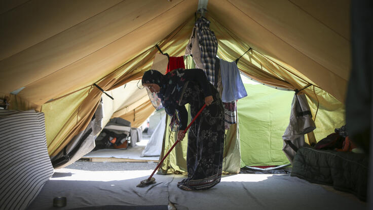 Syrian woman sweeps the floor of her tent in the Alexandria refugee camp