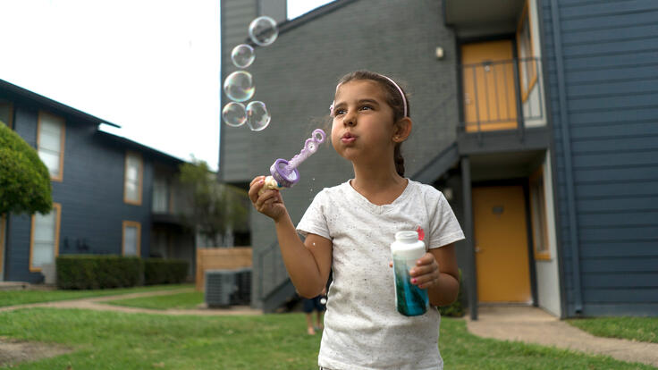Jori blows bubbles outside her family's apartment