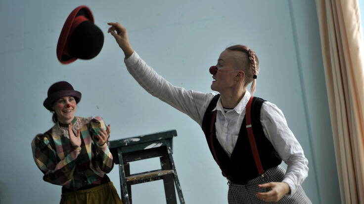 Clowns Nour El-Refai and Jenny Soddu from “Clowns Without Borders” tossing a hat to each other.