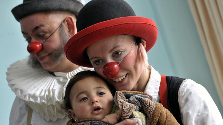 A small child hugging the Clowns Without Borders clowns.