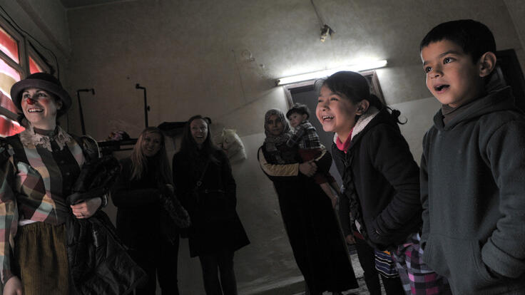 A group of children laughing and having fun watching the Clowns Without Borders.