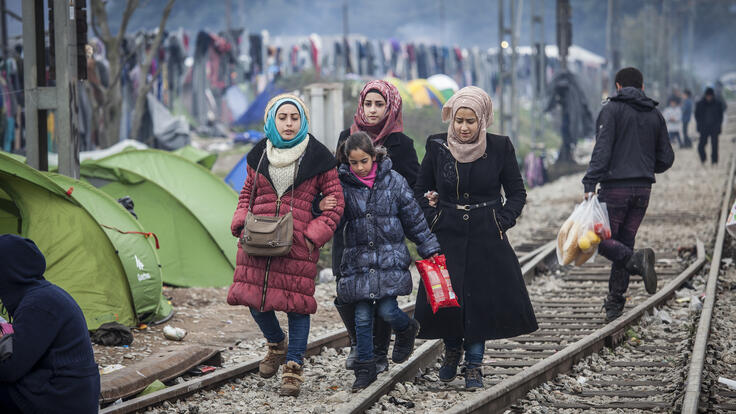 A family of four walking down the train tracks.