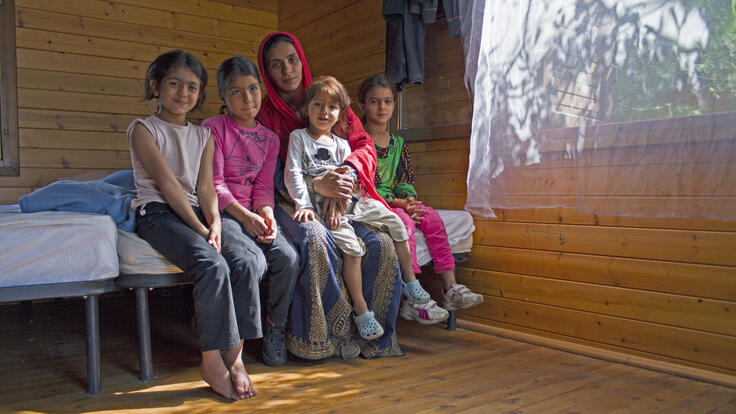 A family of five seated on a bed.