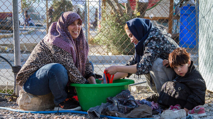 Two women washing clothes, one with a child at her side.