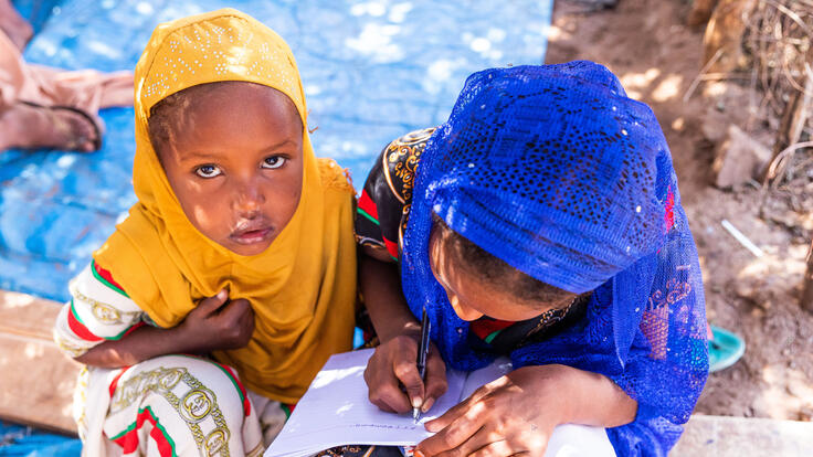 Two children writing in a notebook.