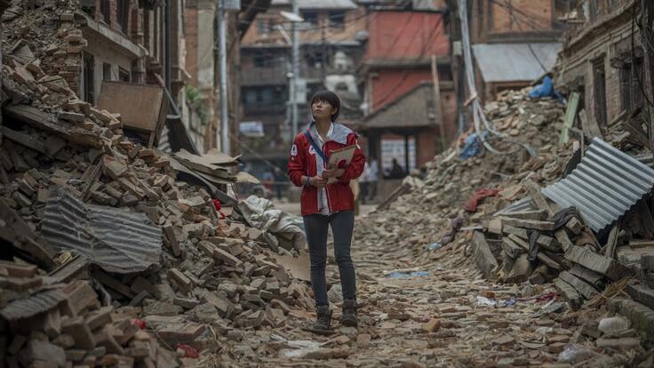 A person standing in the middle of damaged homes.