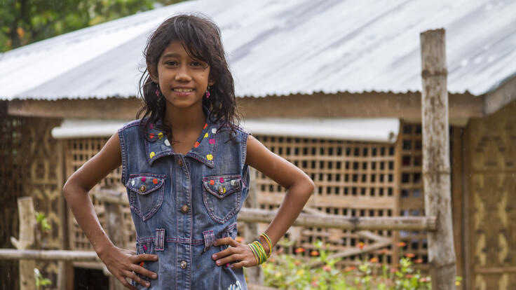 Small child standing in front of repaired home in the seaside village of Agdaliran.