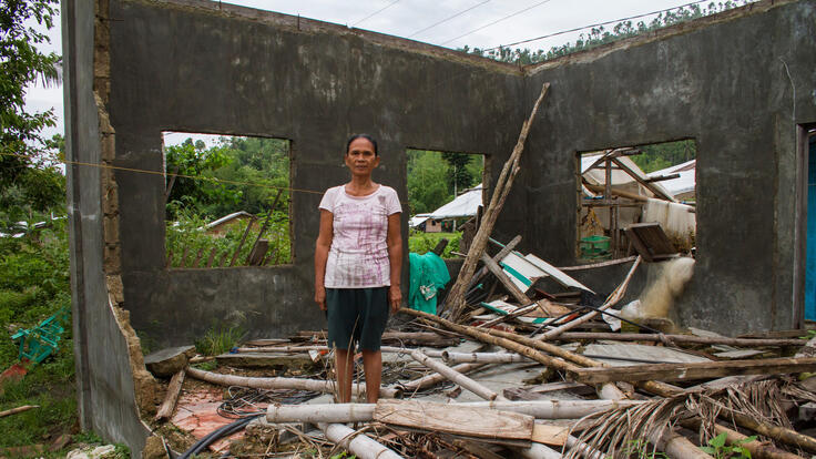 Elsa Azuelo standing in front of the four collapsed walls of her home.