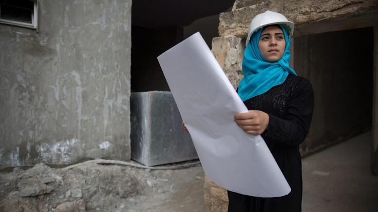 A young girl reading a blueprint.