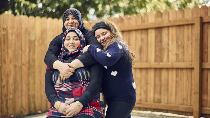 A mother posing with her daughters for a photo.