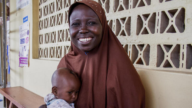 A mother holding her baby and smiling.