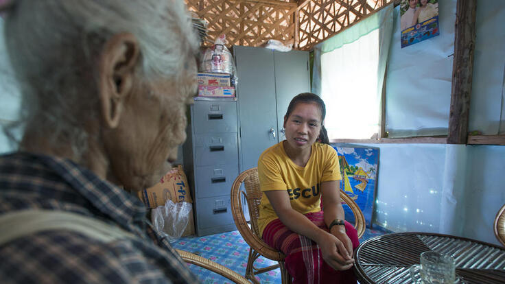 An IRC member seated and speaking to an elderly woman.