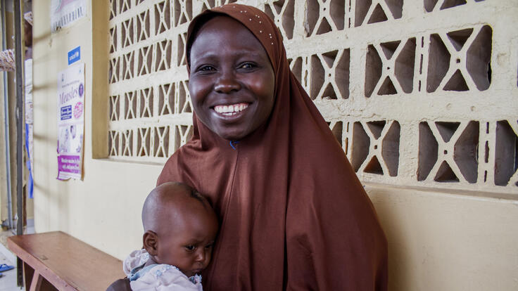 A mother holding her baby and smiling.