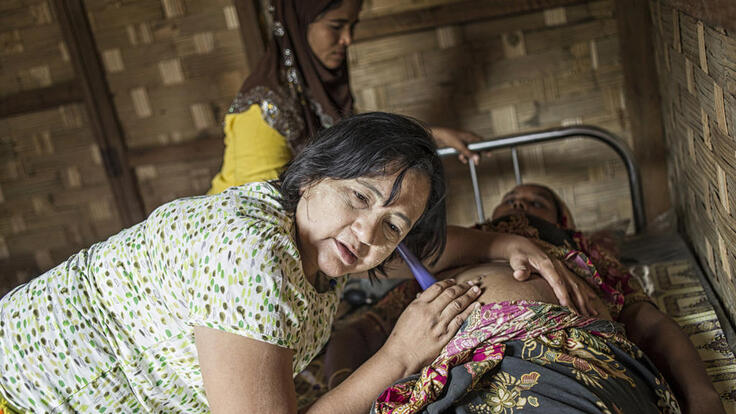 A clinic health worker giving an expectant mother a check-up.