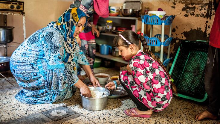 A mother and daughter cooking in a pot.