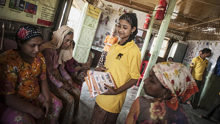 IRC volunteer passing out information packets for critical basic health services.