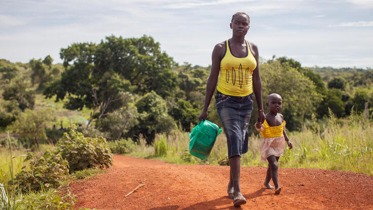 A South Sudanese woman and child walking.