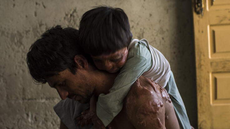 A small child resting on Rahmat's shoulders.