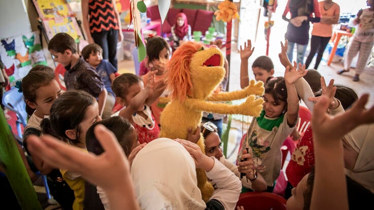 Children excitedly playing with a Muppet.