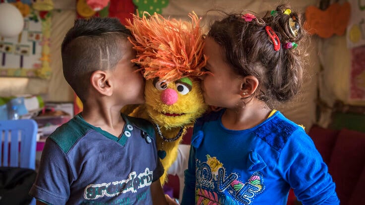 Two children kissing a Muppet.