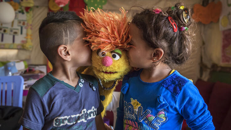 Two children kissing a Muppet.