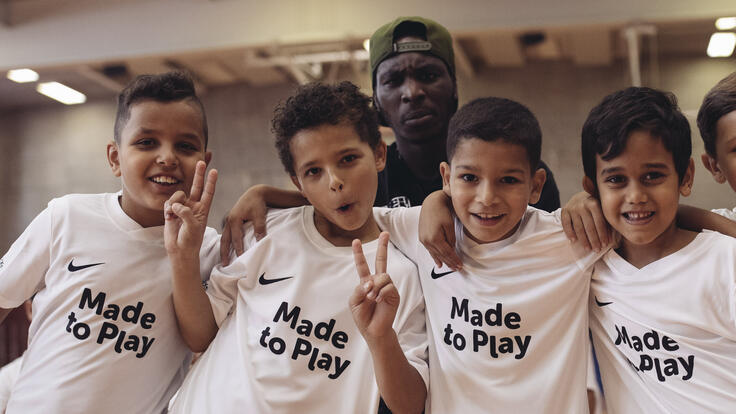 Children posing for a photo wearing "Made to Play" t-shirts.