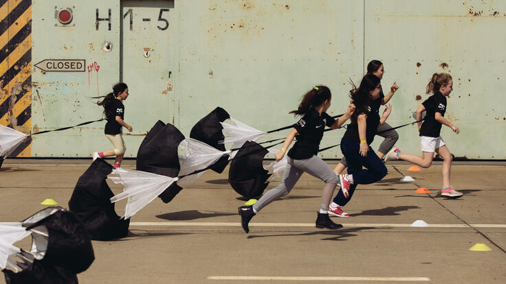 Kids running a parachute race.