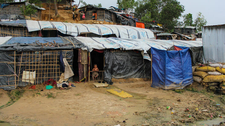 Child glancing outside of a hut.