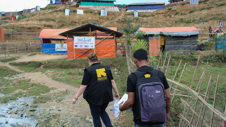 Two IRC medical team members walking up a hill.