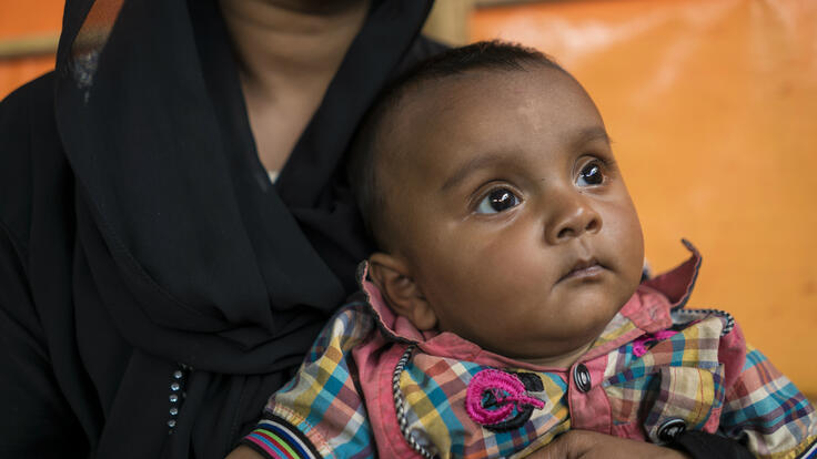 Small child looking off into the distance while being held.