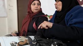 Syrian women look at an IRC-created comic book and discuss decisions the main character makes