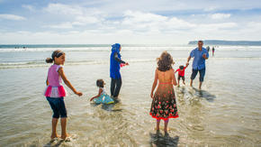 The Tlas family from Syria play in the surf at a California beach 