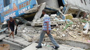 A man and woman walk gingerly past the rubble of buildings in Port-au-Prince, Haiti destroyed by the powerful 2010 earthquake. 