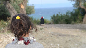 A refugee child on the island of Lebos, in Greece, looks out toward the sea