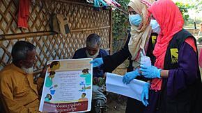 Two IRC community health workers post COVID-19 awareness posters