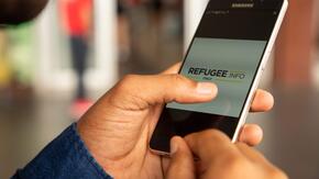 A cellphone showing Refugee.Info site on the screen